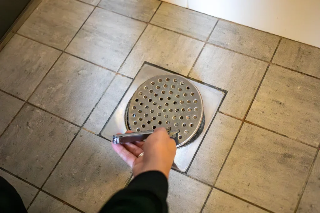 Galler för golvbrunn i badrum plockas bort för att kontrollera avloppet.