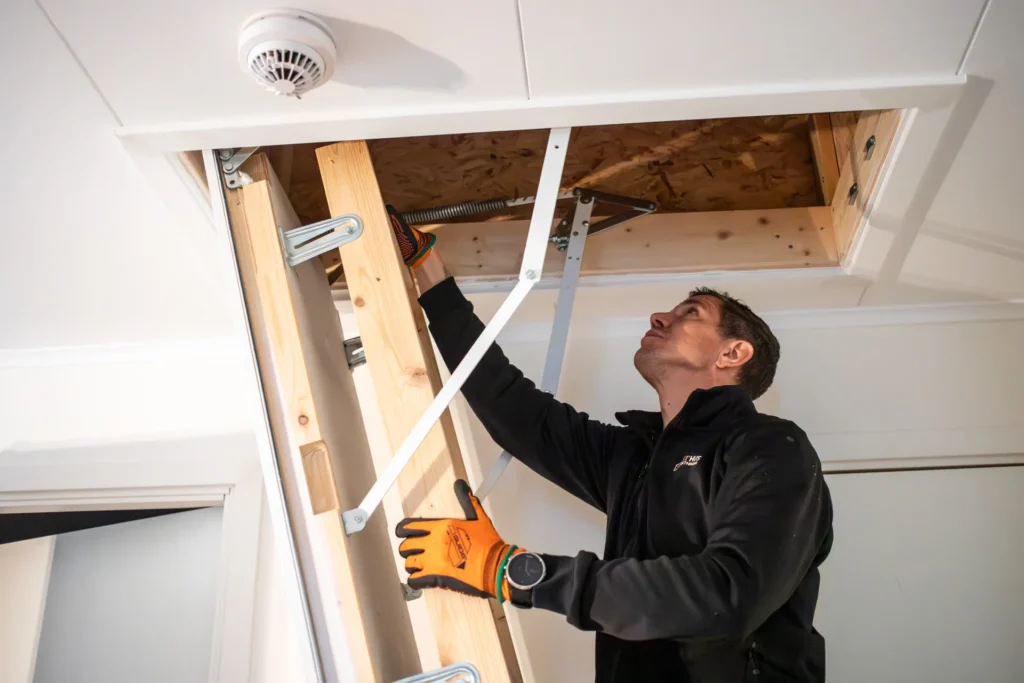 Man klättar upp för stege för att besiktiga vind i villa.